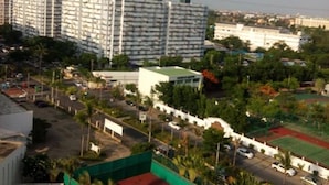 Zona residencial con cancha de tenis, estacionamiento y edificios altos al fondo.