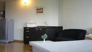 Una habitación de hotel con cama, una mesita, un aparador y un refrigerador.