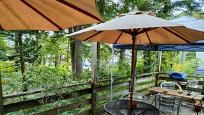 A wooden deck with outdoor furniture, including a round table and chairs, and a pergola with a canopy. - Bellscabin Guesthouse (Karuizawa)