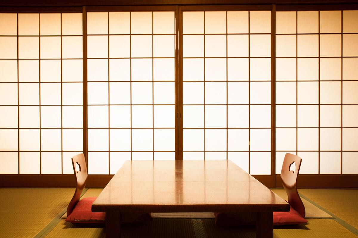 Une pièce de style japonais traditionnel, avec un sol recouvert de tatamis, une basse table en bois et des portes coulissantes en papier de riz (shoji).
