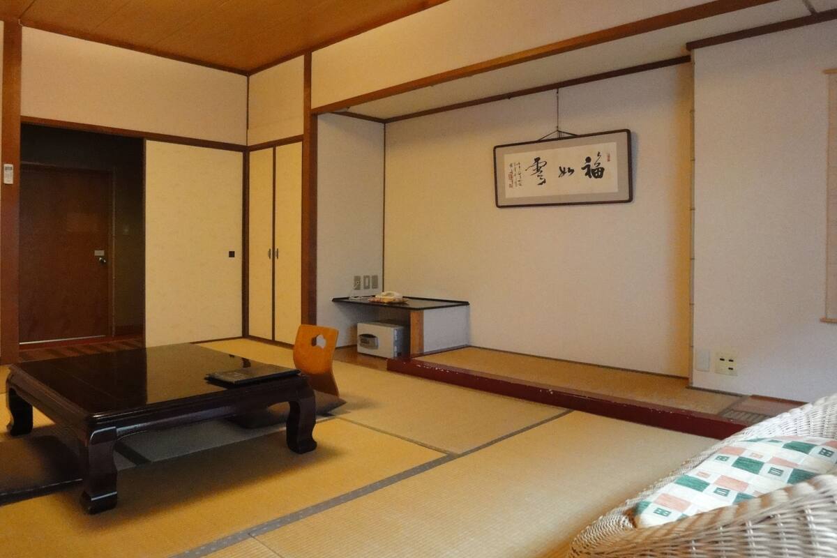 Une pièce de style japonais traditionnel, avec un sol recouvert de tatamis, une table basse, une chaise et un lit.