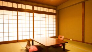 A traditional Japanese room with tatami flooring, a low wooden table, and a sliding door with a grid pattern.