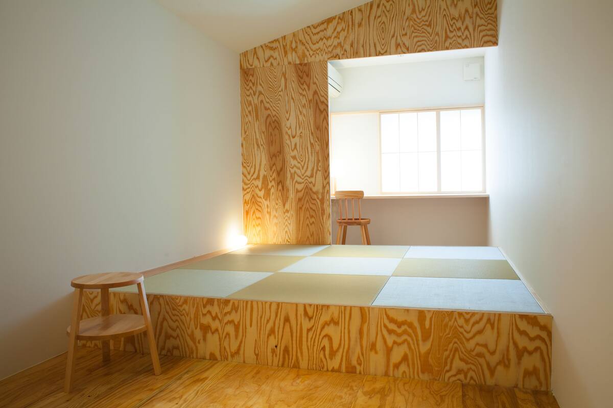 Une pièce avec un plafond en pente, une fenêtre, une chaise en bois et une petite table.