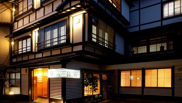 A traditional Japanese building with multiple windows and a well-lit entrance.