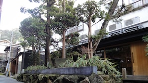 A modern building with a stone retaining wall, large rocks, and a wooden staircase leading to a wooden door.