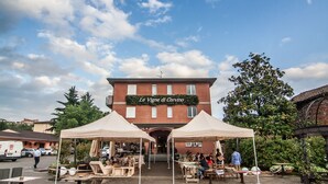 A building with a sign reading "Le Vigne di Corvino" and outdoor seating under two tents. - Hotel Le Vigne di Corvino (Corvino San Quirico)