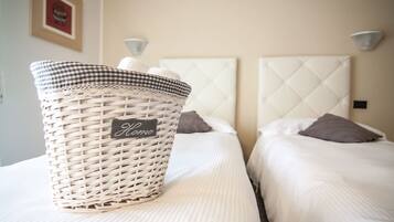 Una cama bien hecha con una cesta de mimbre que dice 'Home' a su lado.
