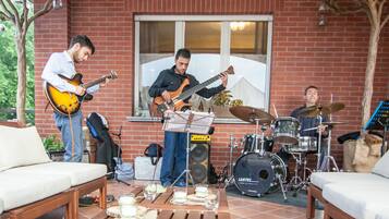 Un groupe de musique jouant sur une terrasse dont les murs sont en briques, avec une batterie et divers instruments de musique.