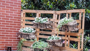A wooden deck with a white bench, surrounded by wooden pallets used as planters with various plants. - Hotel Le Vigne di Corvino (Corvino San Quirico)