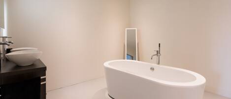 A modern bathroom with a freestanding bathtub, a dark wooden vanity, and a large mirror.