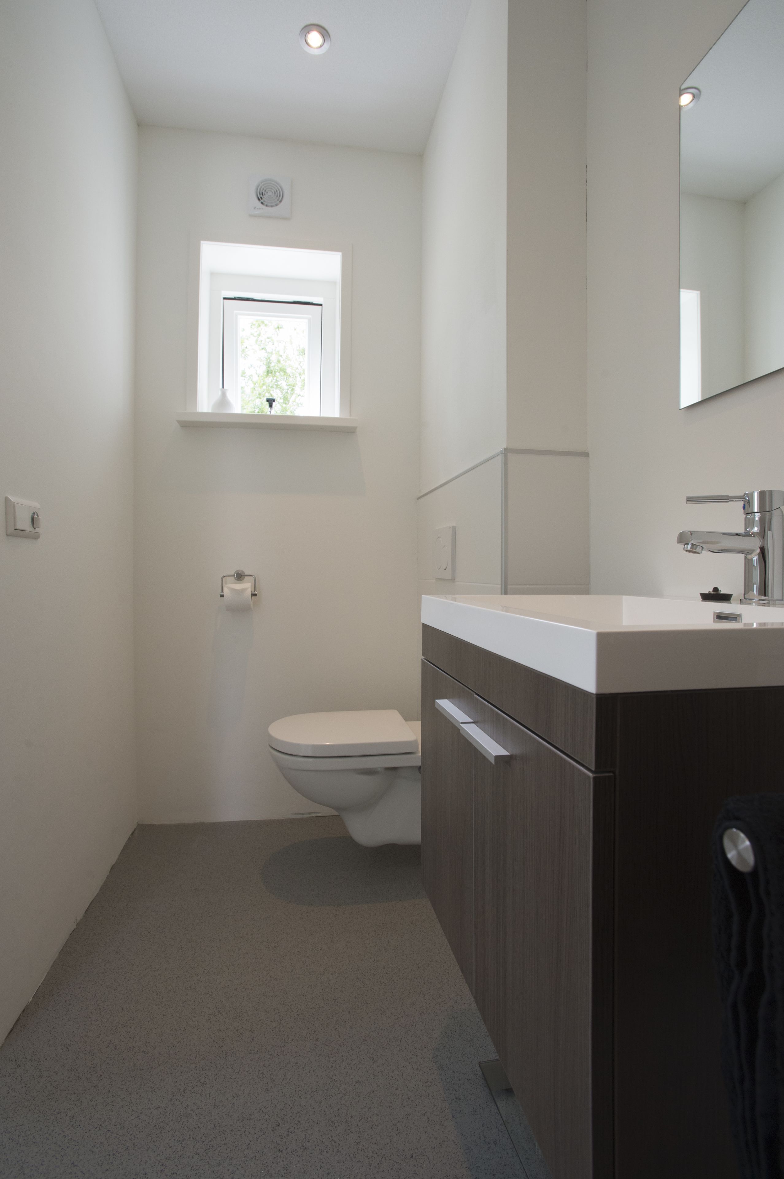 Un baño moderno con inodoro, lavamanos y espejo.
