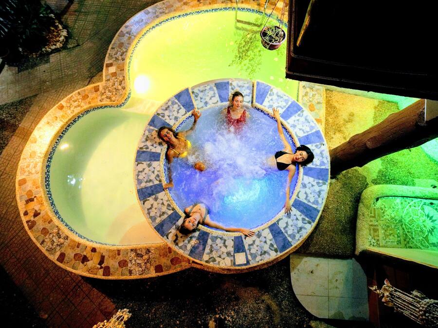 Un jacuzzi circular con mosaicos, rodeado de un suelo de baldosas y un sofá verde.