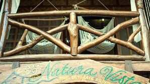 Un balcón de madera con una hamaca y un letrero que dice "Natura Vista".