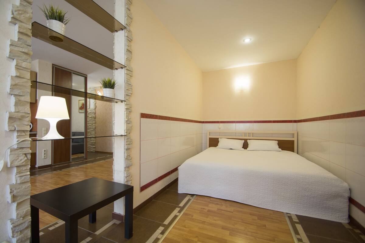 Una habitación de hotel con una cama, una mesa y una lámpara.