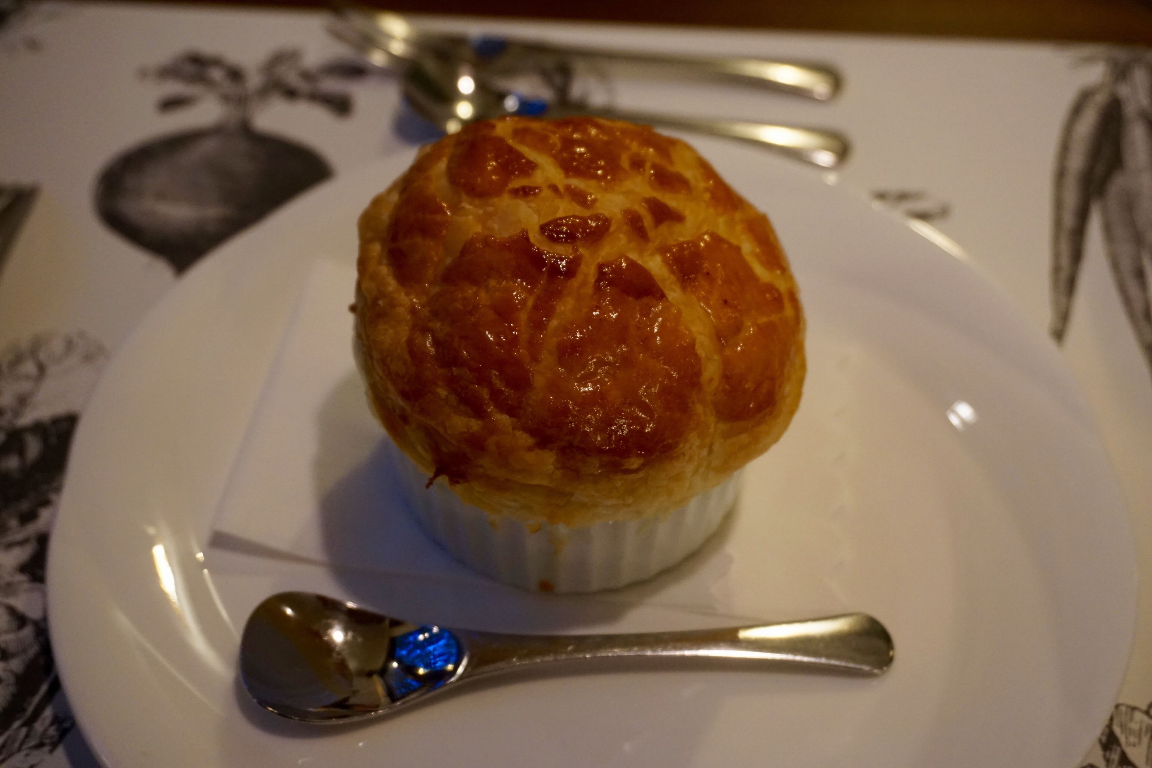 Ein Dessert auf einem weißen Teller mit einem Löffel daneben.