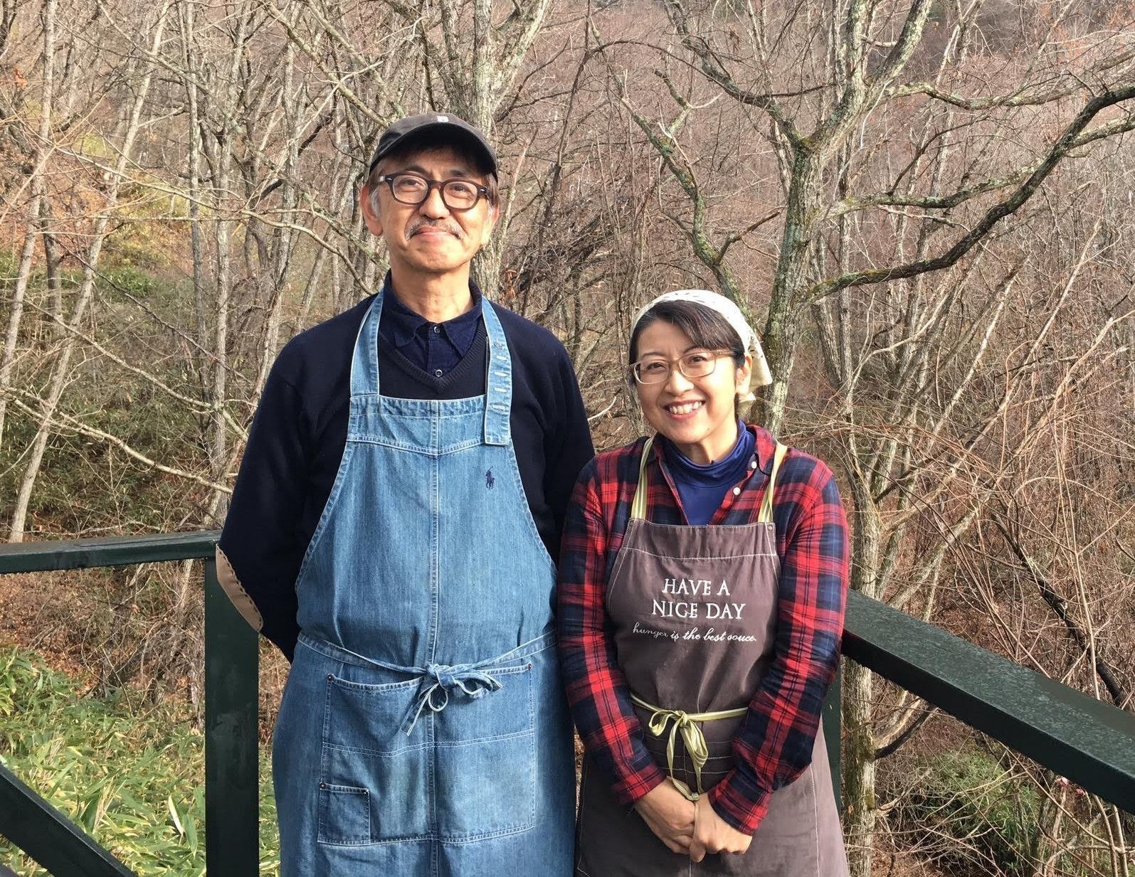 Two people standing on a bridge with bare trees in the background.