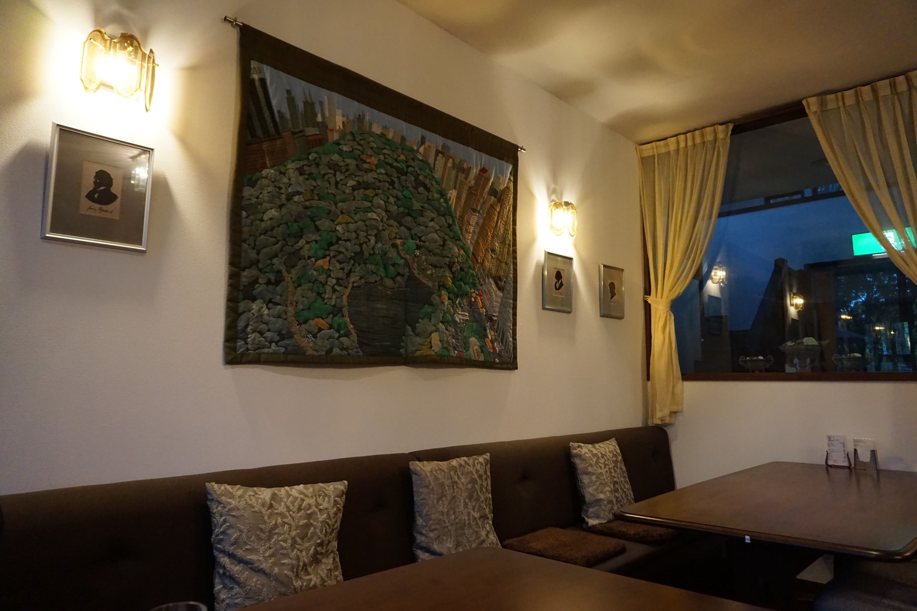 En restaurang med en inredning som inkluderar en väggmålning i sten, bekväma sittplatser och inramade tavlor.