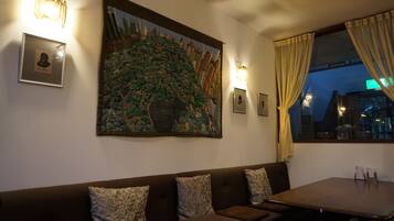 En restaurang med en inredning som inkluderar en väggmålning i sten, bekväma sittplatser och inramade tavlor.