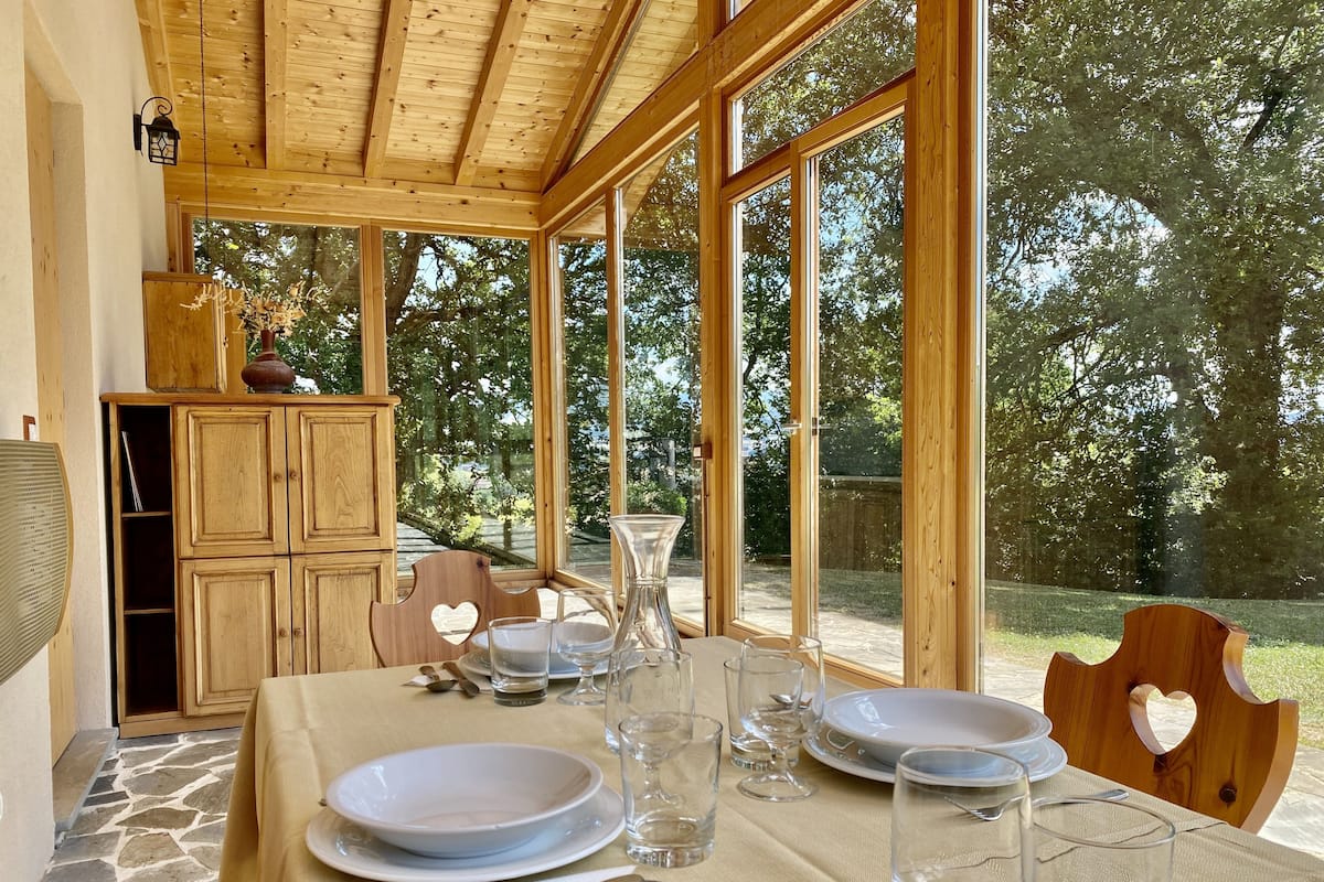 A dining area with a table set for four, large windows, and a wooden cabinet.