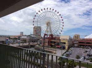A Ferris wheel in an urban setting with buildings and a parking lot. - Utopia Mihama (Chatan)