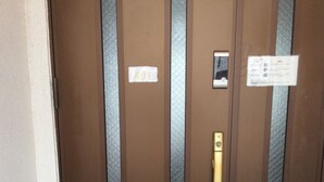 A brown door with a gold handle, a number plate, and a small sign.