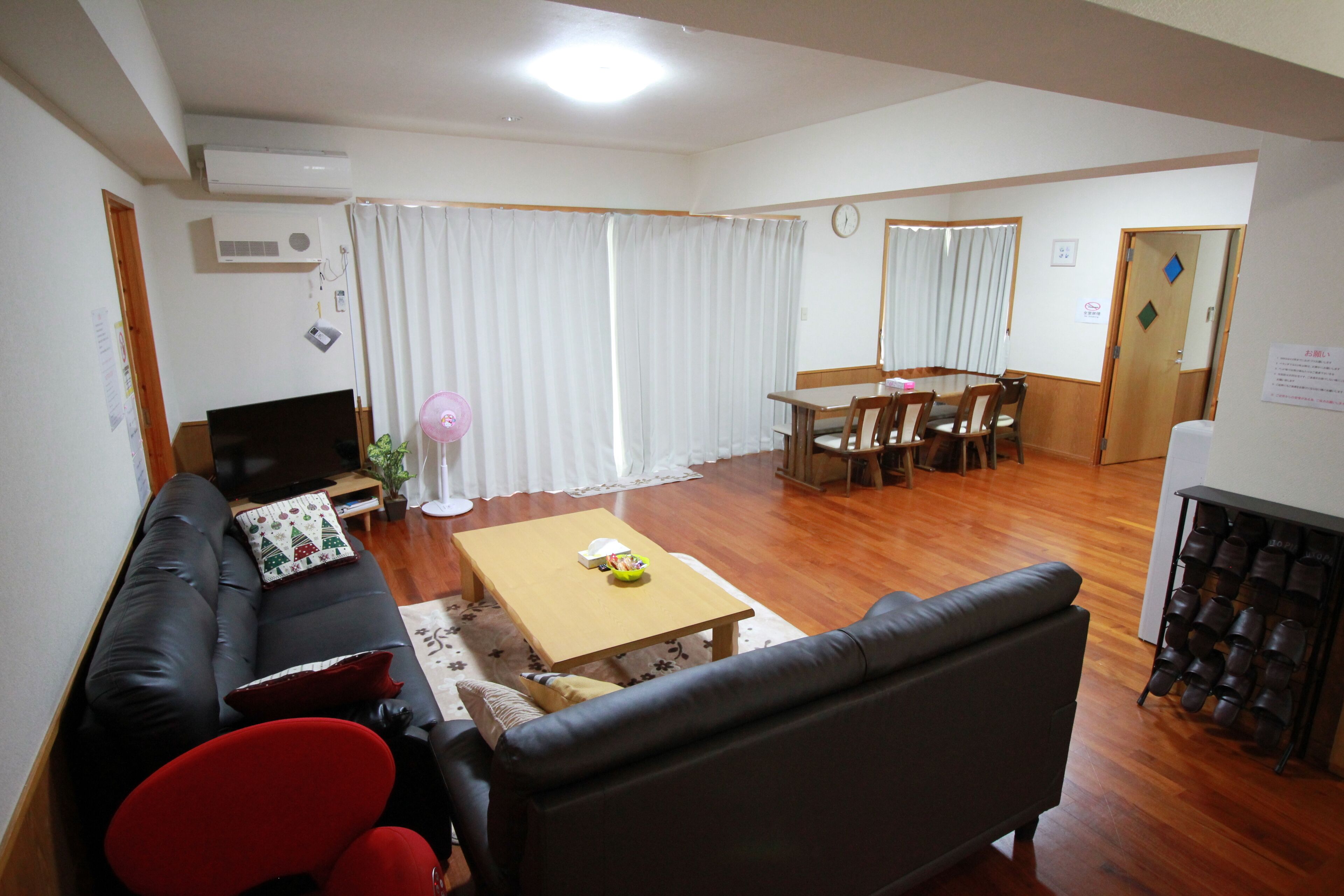 A living room with a sofa, a coffee table, a TV, and a dining area with chairs and a table.