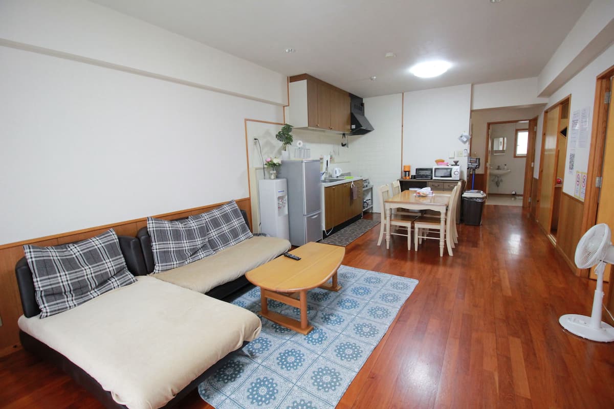Un espacio habitable compacto con sofá, una mesita, kitchenette y comedor.