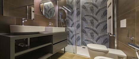 A modern bathroom with a large mirror, a sink, a toilet, and a shower area.