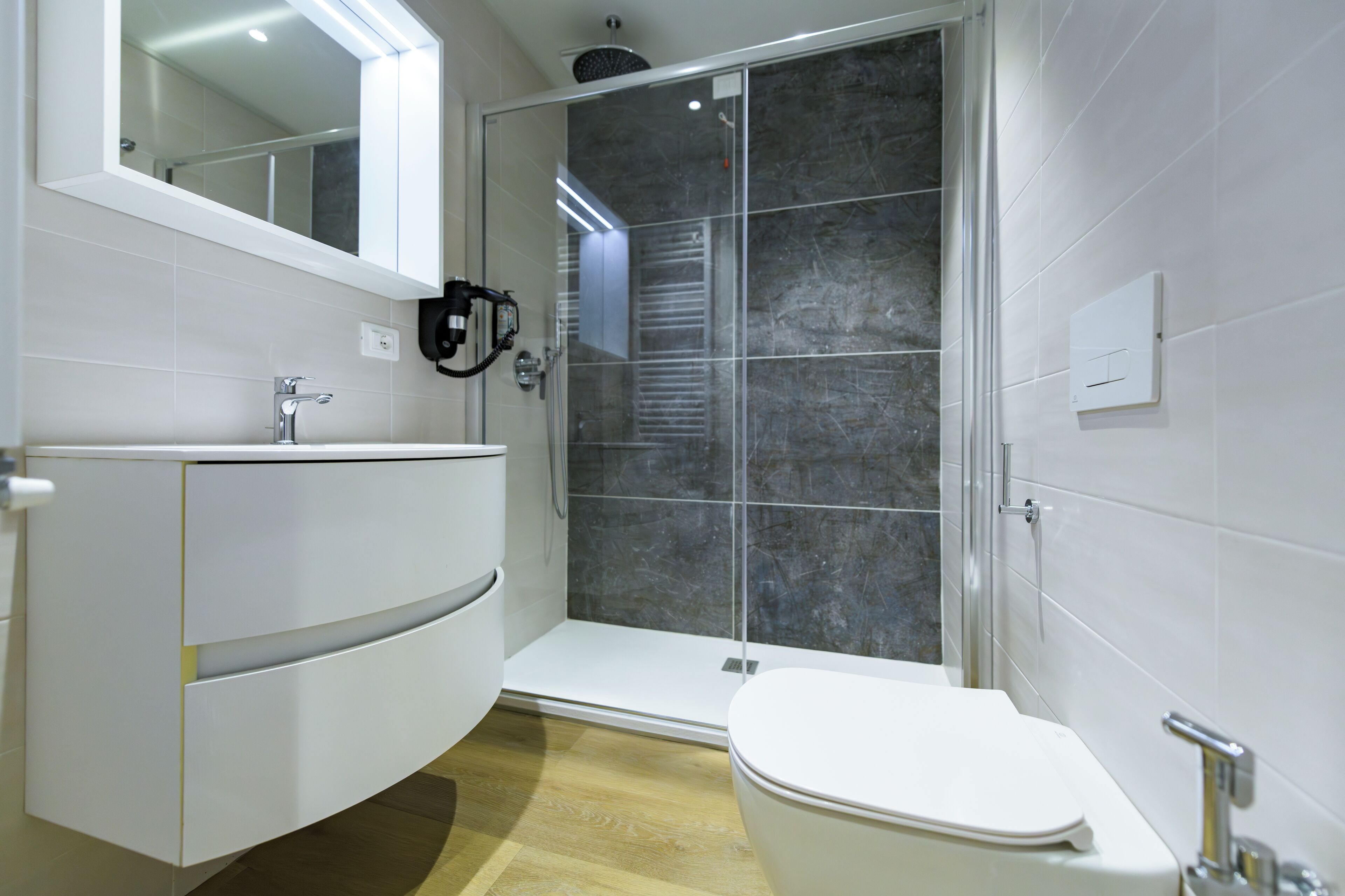 Un baño moderno con tocador blanco, cabina de ducha de vidrio y inodoro.
