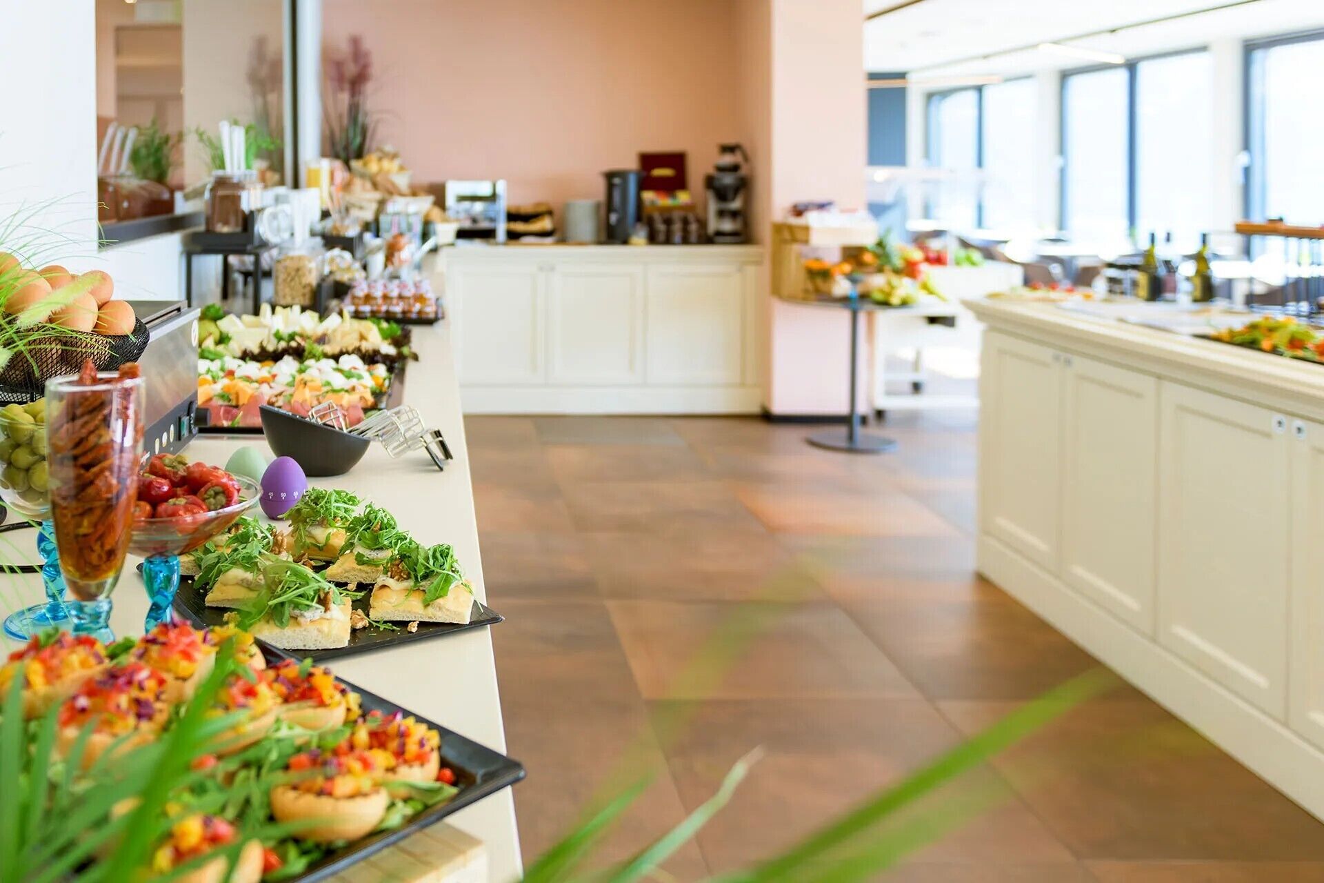 A buffet with various food items and a kitchen area in the background.
