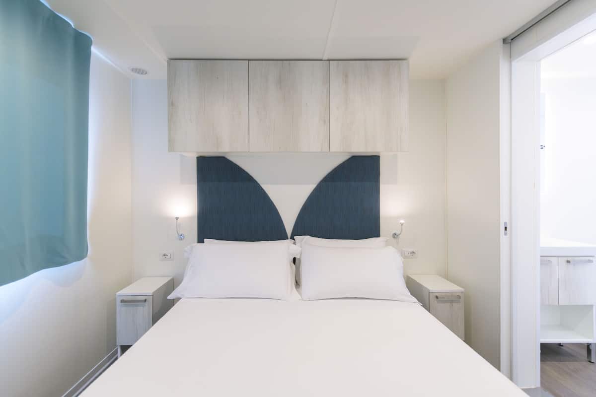 Ein modernes Schlafzimmer mit Bett, Nachttischen und einem Kleiderschrank.