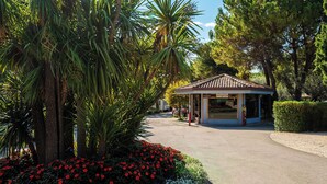 Un petit bâtiment d’un seul étage, avec un toit en tuiles, probablement un hôtel ou une maison d’hôtes, entouré d’une végétation luxuriante et de fleurs rouges.