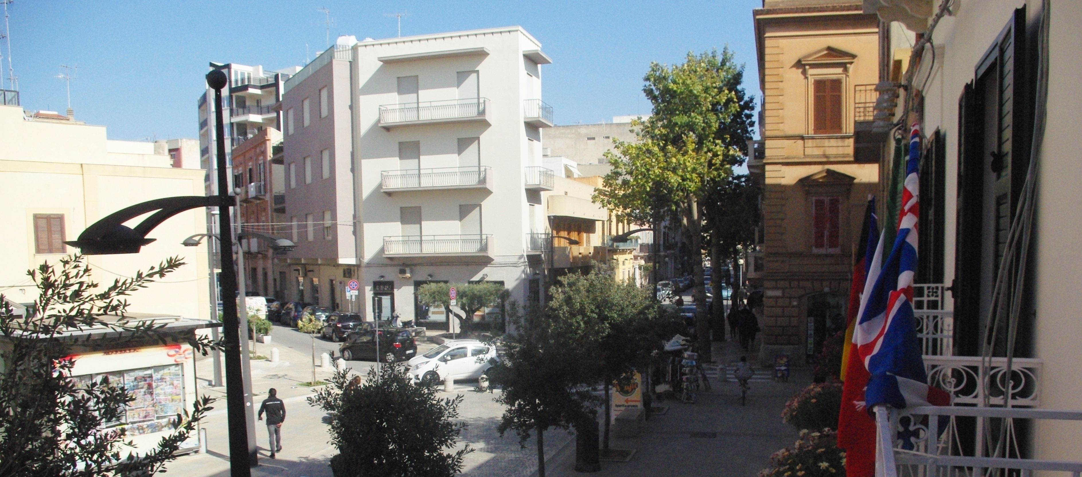 A street view with buildings, a pedestrian, and parked cars.