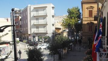 A street view with buildings, a pedestrian, and parked cars.