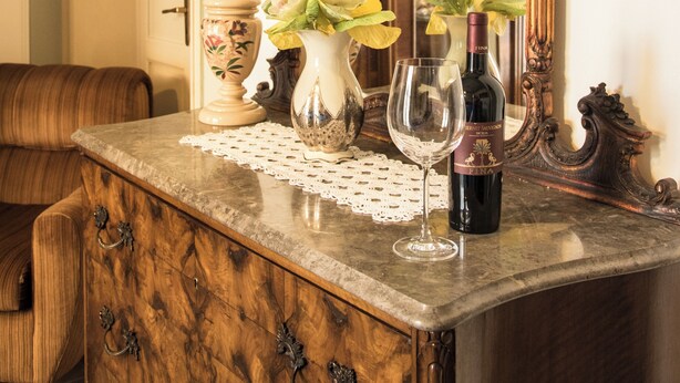 A wooden dresser with a vase of flowers and a wine bottle. - B&B Via Roma (Marsala)