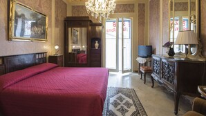 A spacious bedroom with a large bed, a chandelier, a television, and a dresser. - B&B Via Roma (Marsala)