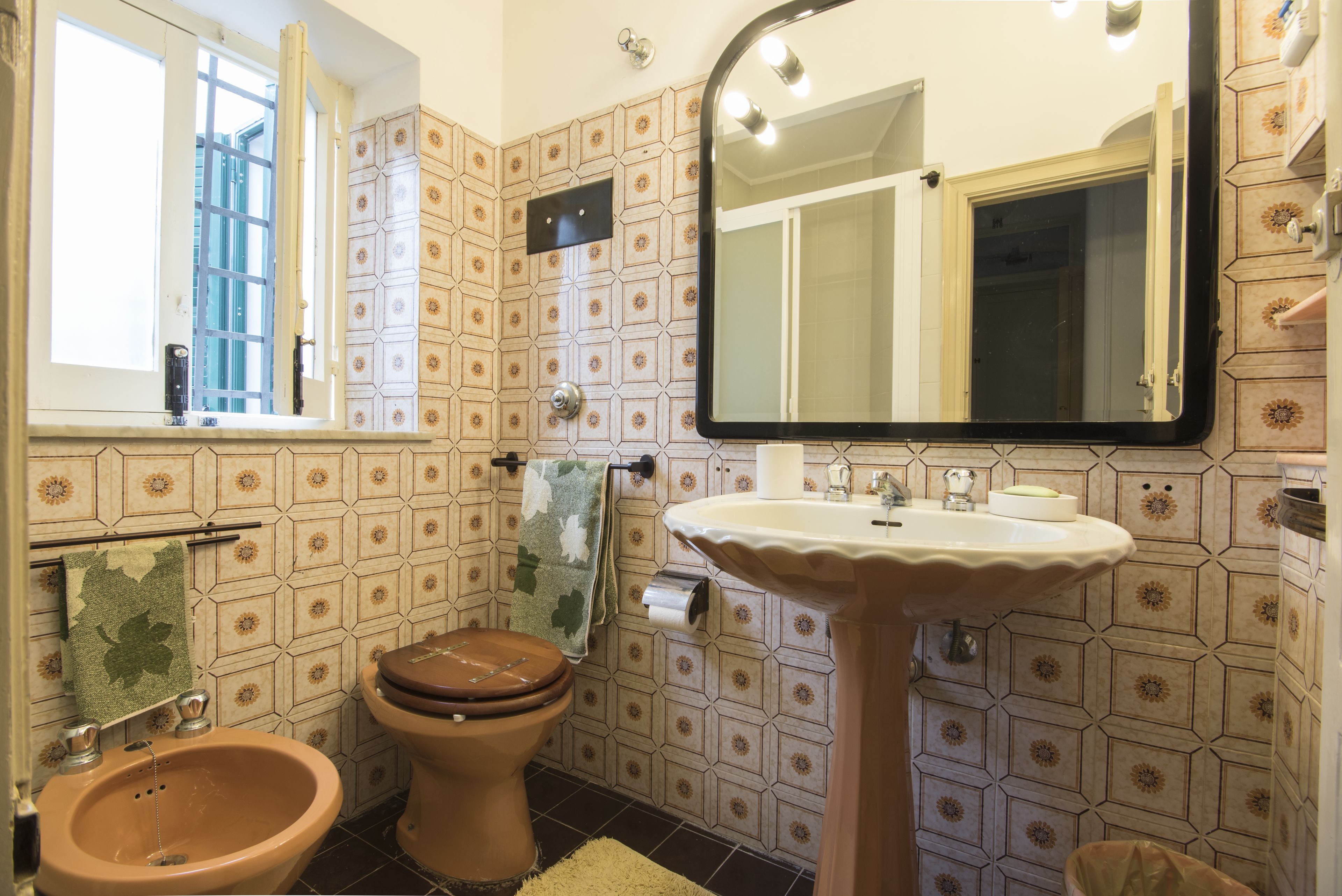 A bathroom with a toilet, bidet, sink, and mirror.