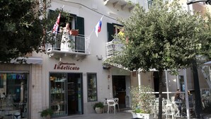 A building with a storefront named 'Pasticceria Indelicato'. There are outdoor tables and chairs, and a tree in front of the building. - B&B Via Roma (Marsala)
