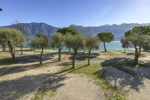A park with trees and a lake, surrounded by mountains. - Camping Park Garda (Limone sul Garda)