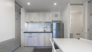 A modern kitchen with white cabinets, a stainless steel refrigerator, and a white countertop.