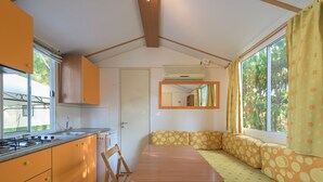 A compact kitchen with a dining area, a built-in stove, and a window with curtains.