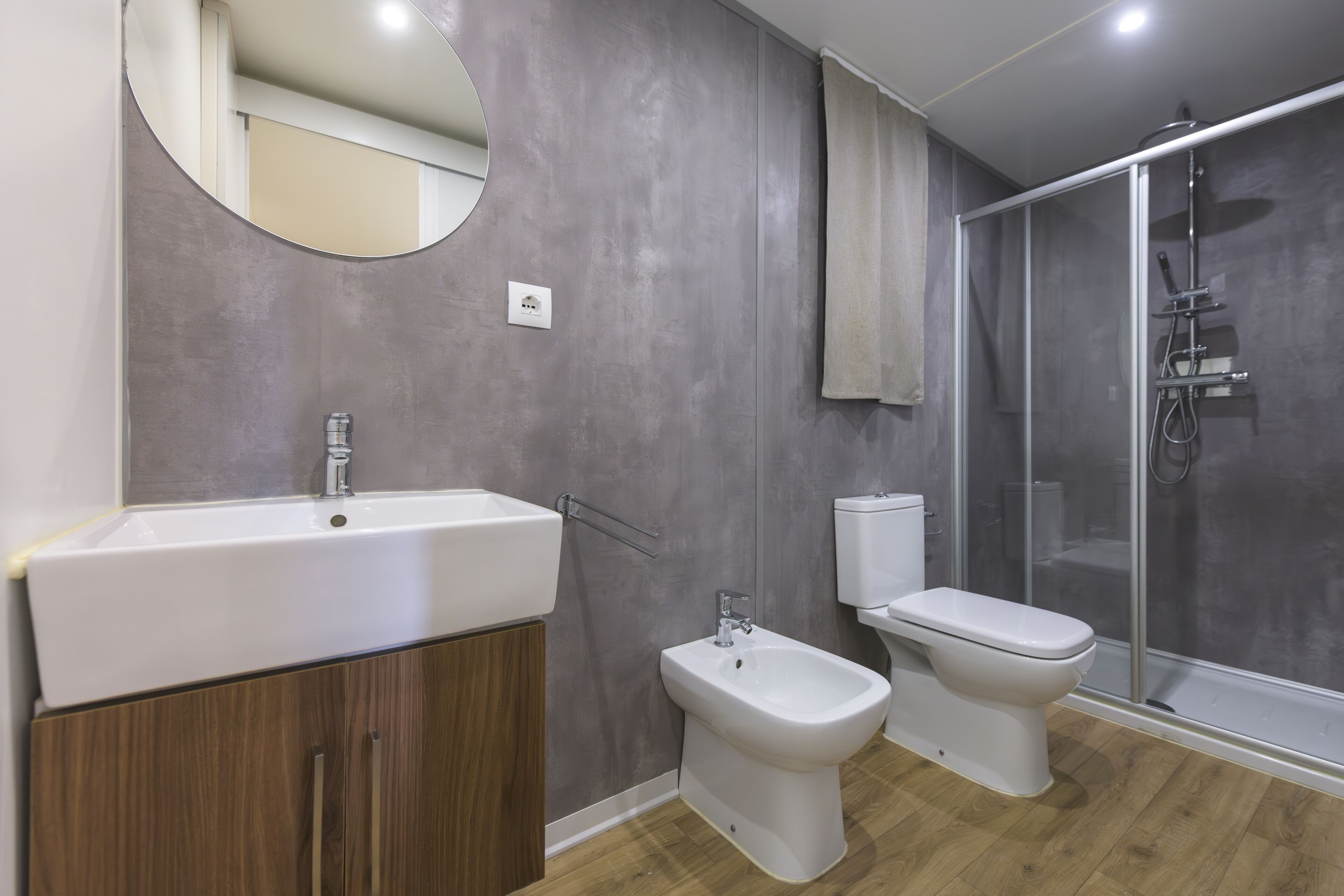Een moderne badkamer met een groot wastafel, een toilet, en een douche met glazen wanden.