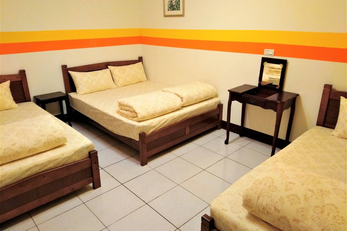 Een hotelkamer met twee eenpersoonsbedden, een nachtkastje en een klein tafeltje met een spiegel.