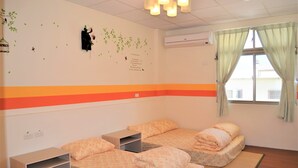 A room with two beds, a small table, and a window with curtains.