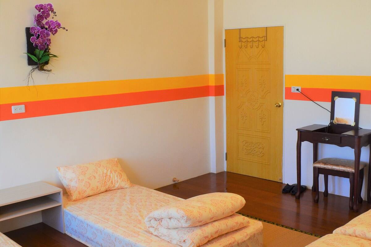 Een kamer met tatami matten, een bed, een stoel en een houten deur.