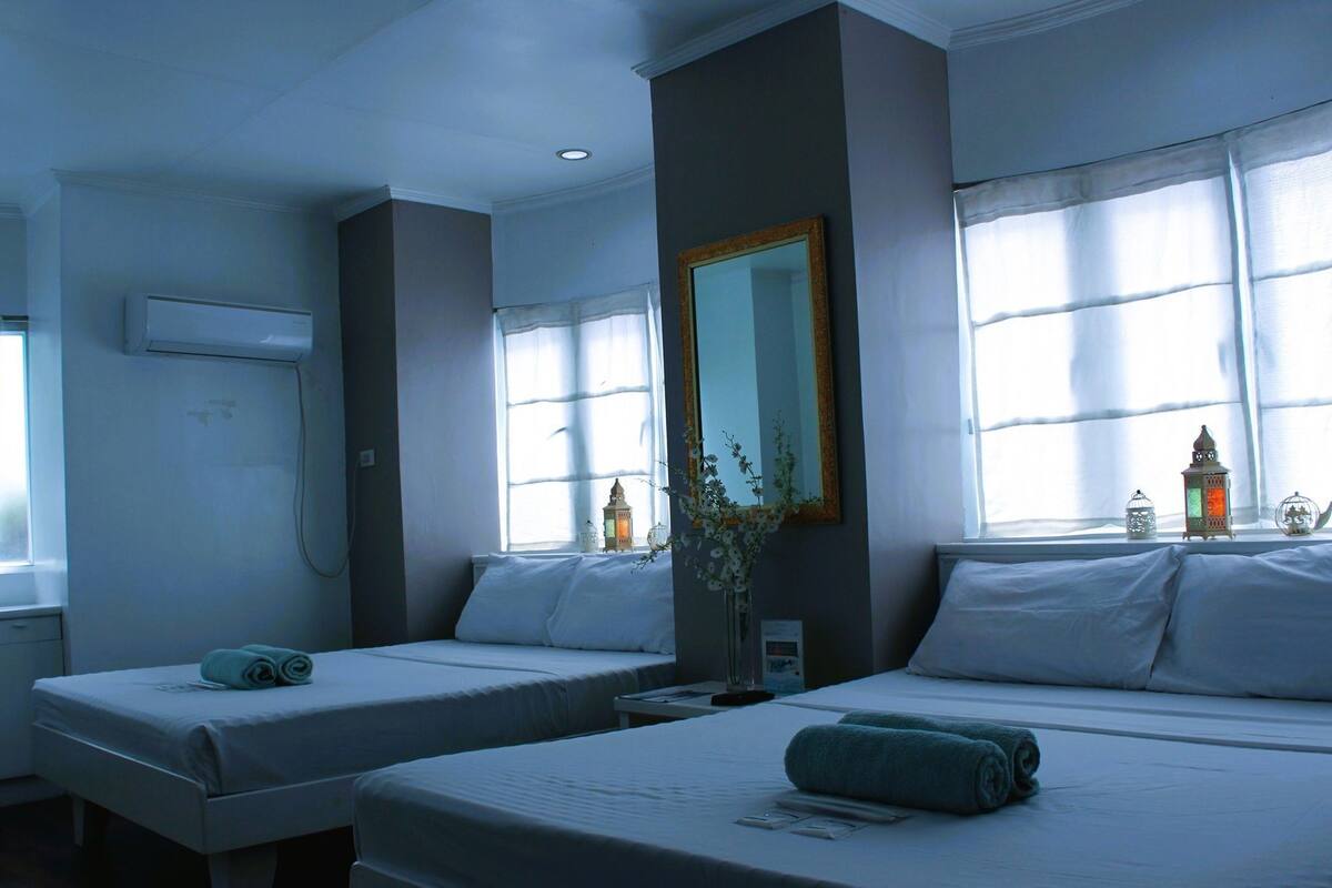 Une chambre d’hôtel avec deux lits, un grand miroir et des objets décoratifs sur le rebord de la fenêtre.