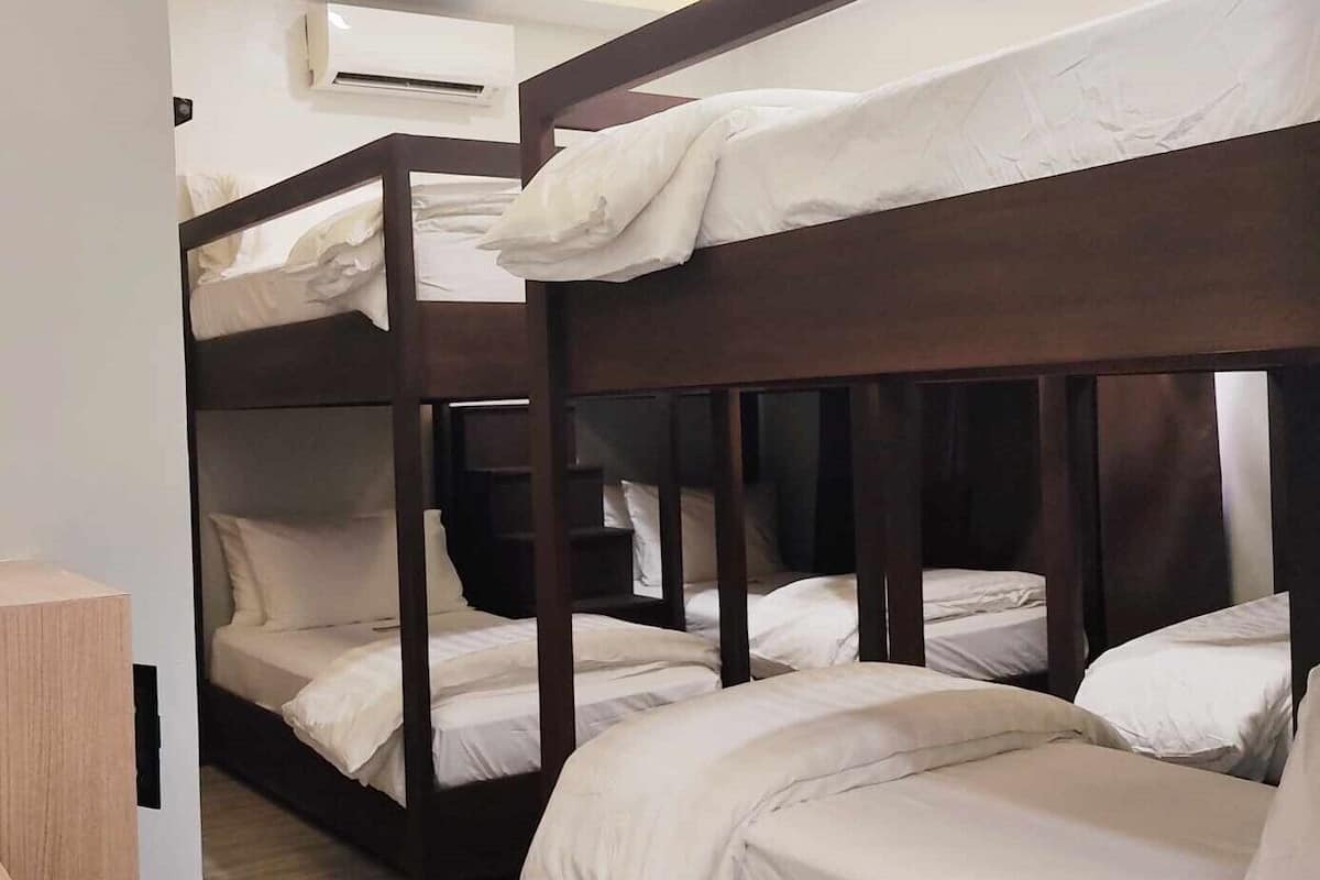 Une chambre avec un lit superposé, dont les structures sont en bois et la literie est blanche.