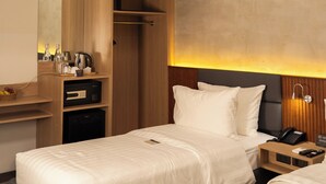 Una habitación de hotel moderna con dos camas, un armario empotrado, un escritorio con hervidor y un balcón pequeño.