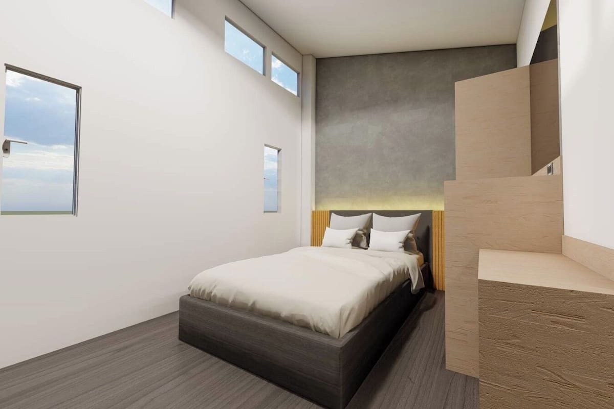 Une chambre moderne avec un grand lit, une tête de lit intégrée et un petit coin salon agrémenté d’un banc en bois.