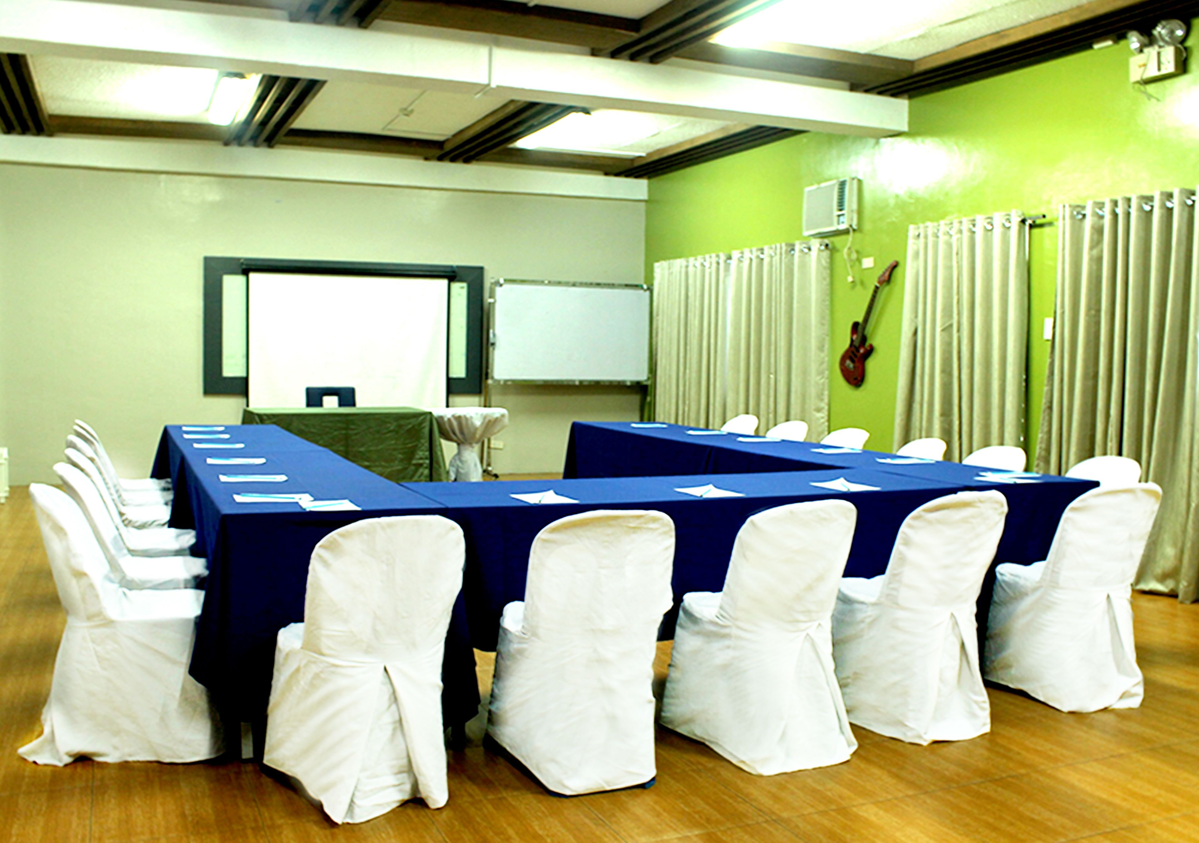 A conference room with a long table and chairs, a whiteboard, and a guitar on the wall.